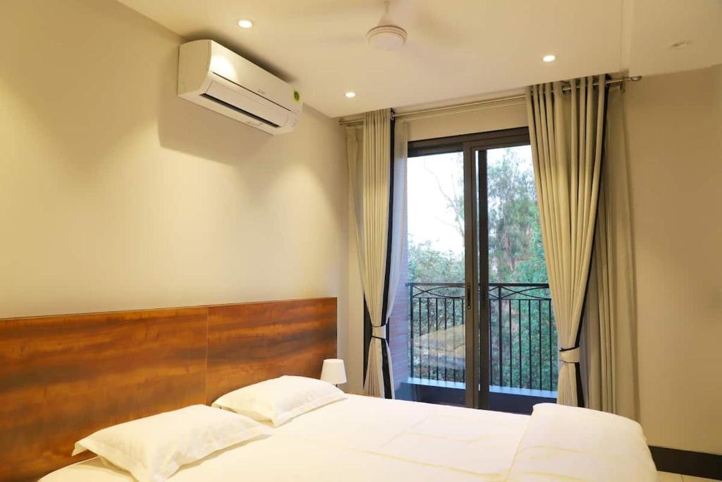 a bedroom with a bed and a window with a balcony at Apt# ONE-FOUR-TWO - with Lift - High Speed Wifi - Smart TV in New Delhi