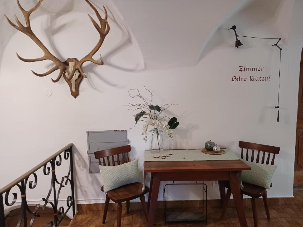 a dining room table with two chairs and a deer head on the wall at Hotel Garni Löwen in Silz