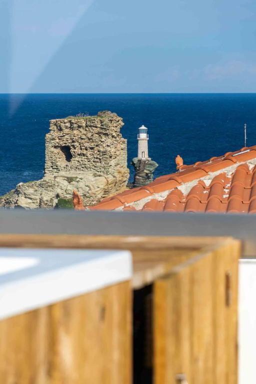 widok na latarnię morską i budynek z latarnią morską w obiekcie Castel Abaso Boutique Apartments by Explore Andros w mieście Andros
