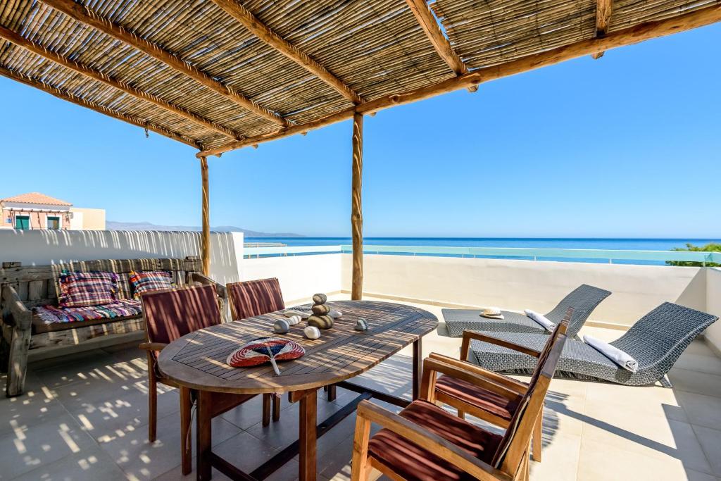 a patio with a table and chairs on the beach at Ilias Apartments in Platanias