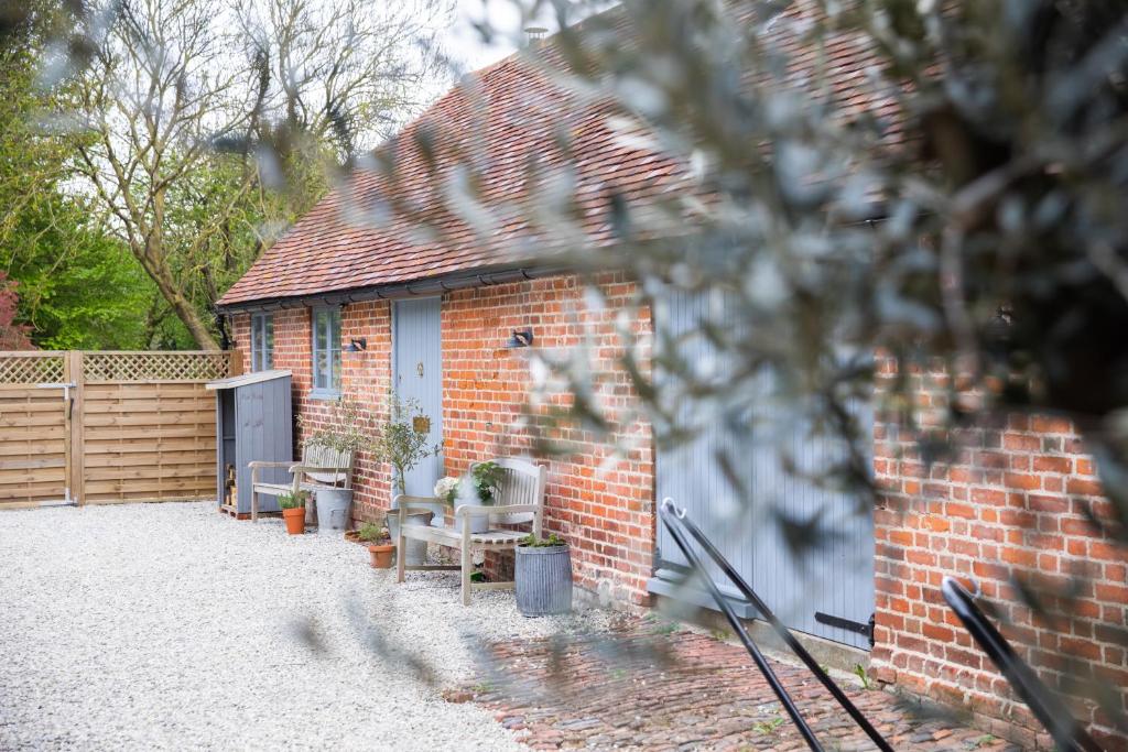 海斯的住宿－The Cowshed Port Lympne，前面有一张桌子和椅子的砖砌建筑