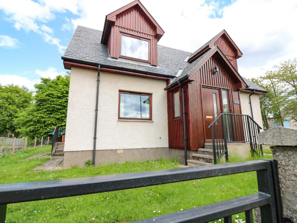 a house with a fence in front of it at Tombeck in Tomintoul