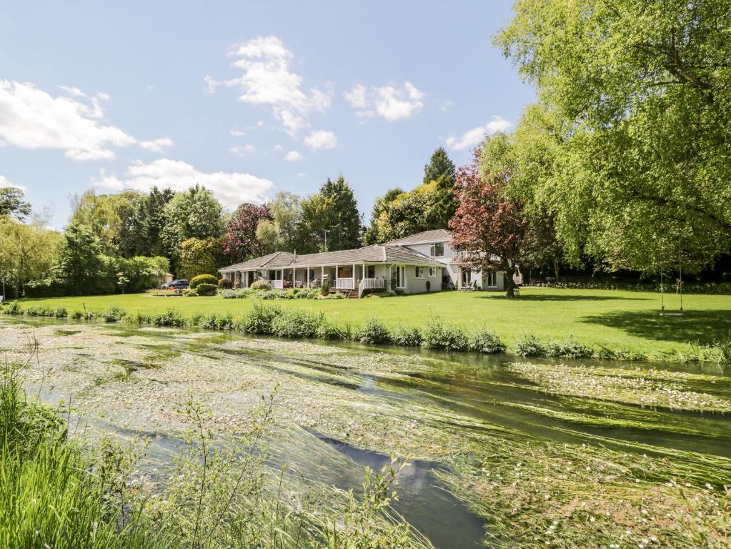 une maison sur une pelouse à côté d'une rivière dans l'établissement The River House Avon Valley Stonehenge with fishing, à Salisbury