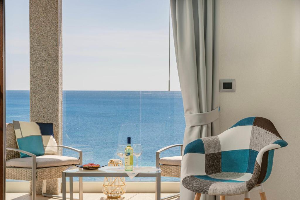 un soggiorno con tavolo, sedie e una grande finestra di Hotel Ristorante La Conchiglia a Cala Gonone