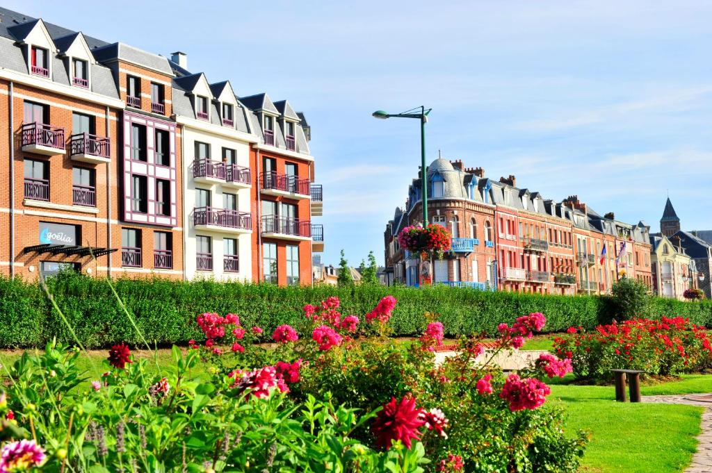 a row of buildings with flowers in a park at Résidence Goélia Belle Epoque in Mers-les-Bains
