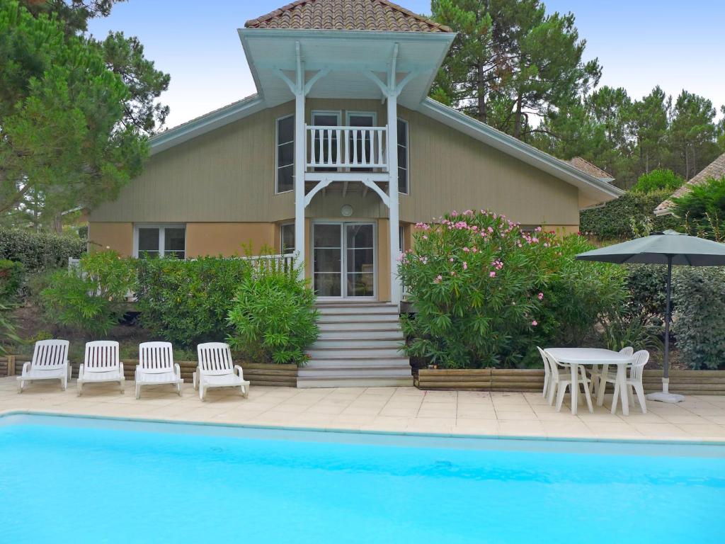 une maison avec une piscine en face d'une maison dans l'établissement Villa Eden Club by Interhome, à Lacanau-Océan