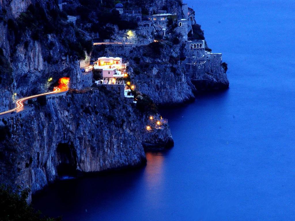 a group of buildings on a cliff next to the water at La Locanda Del Fiordo in Furore