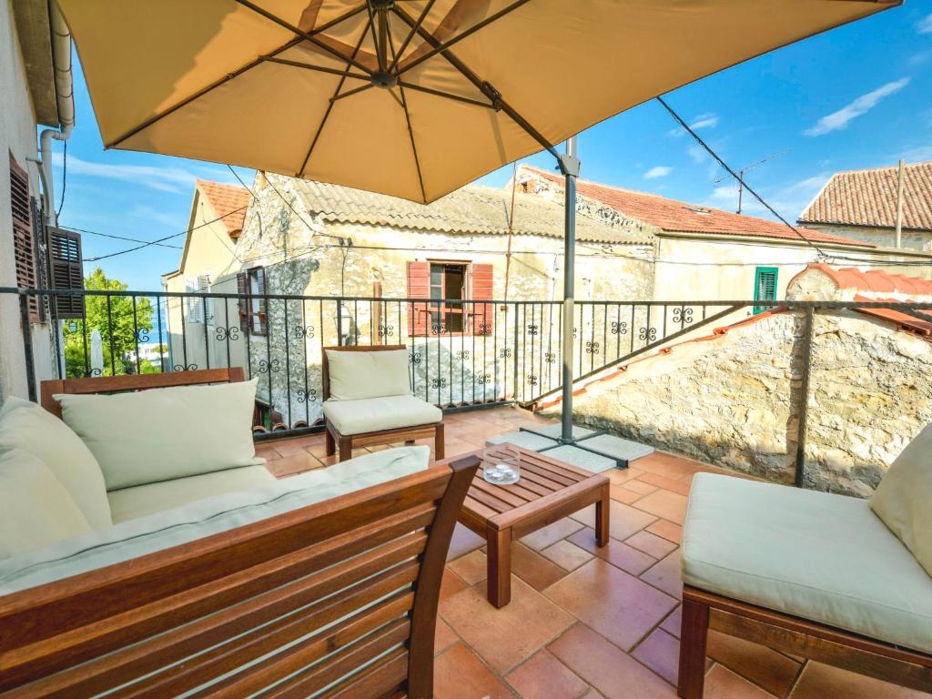 patio z krzesłami i parasolem na balkonie w obiekcie Holiday Home Mali dvori by Interhome w mieście Diklo