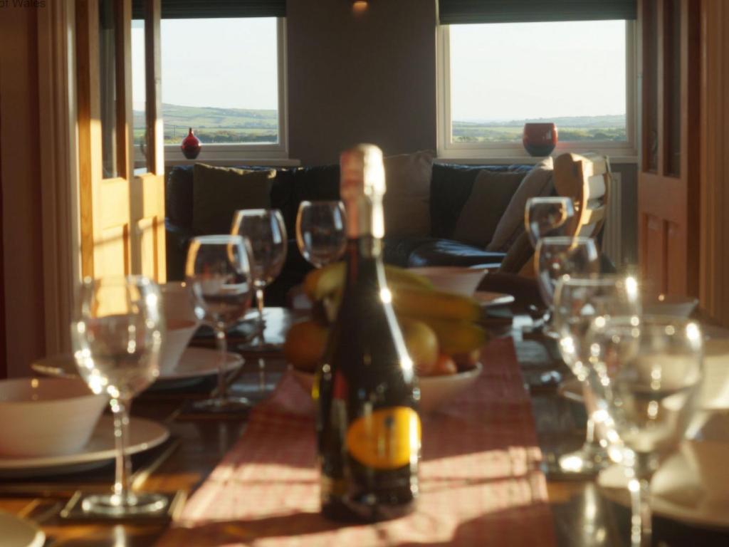 LlangwnadlにあるHoliday Home Brandy by Interhomeのワイングラス付きのテーブルに座ったワイン1本