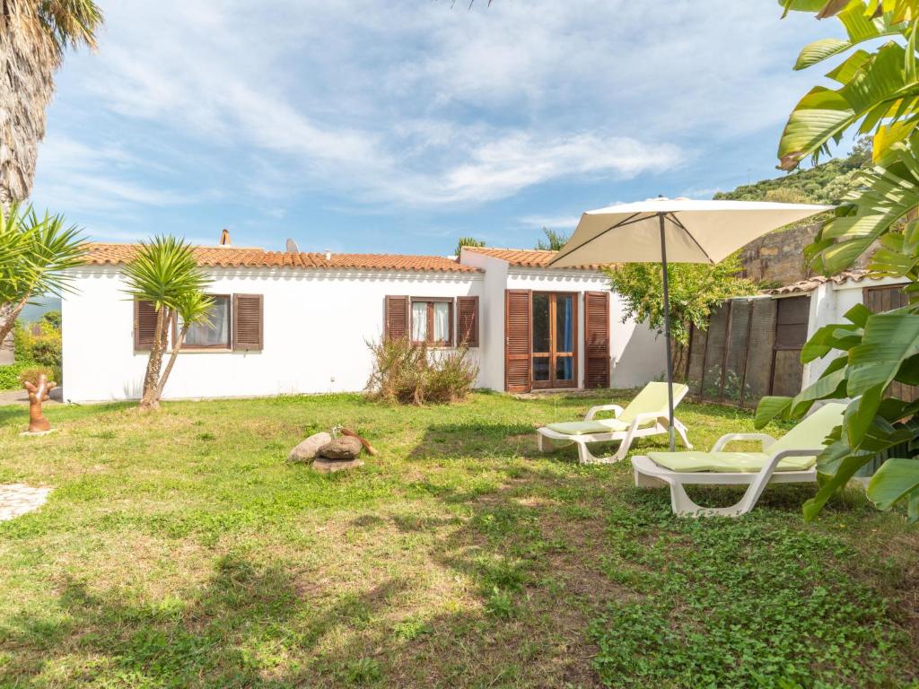 a yard with two chairs and an umbrella at Holiday Home Sibilla by Interhome in Pedrumalu