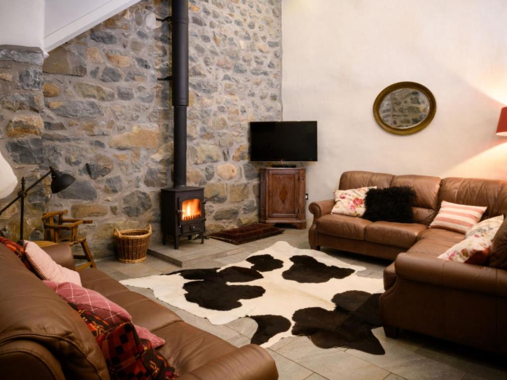 a living room with couches and a stone wall at Holiday Home Bryniel by Interhome in Sarn