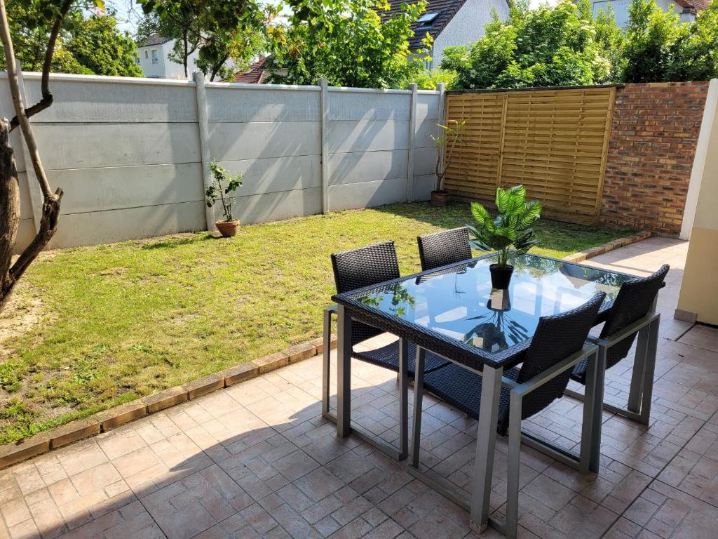 uma mesa de vidro e cadeiras num pátio em charmant studio de 30 m2 très calme avec sa grande belle terrasse et son jardin PRIVATIF em Tremblay En France