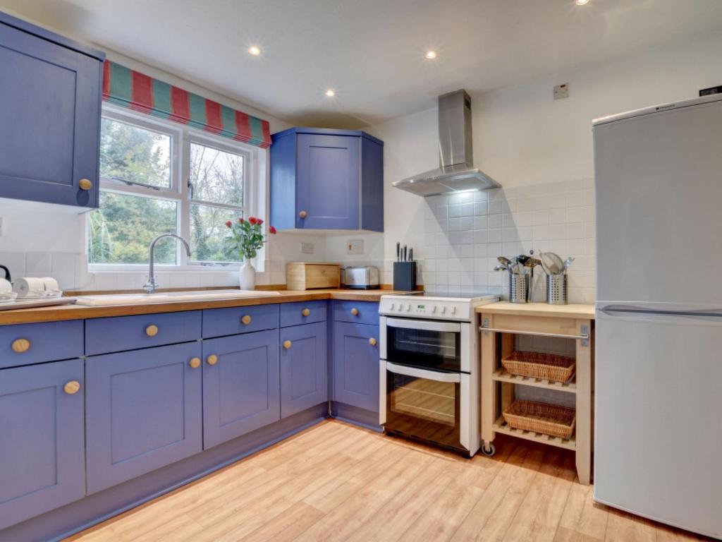 GeorgehamにあるHoliday Home Salar Cottage by Interhomeのキッチン(青いキャビネット、白い冷蔵庫付)