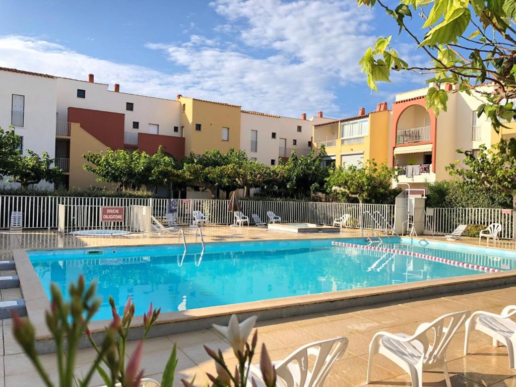 a swimming pool with chairs and buildings in the background at Apartment Santa Monica 1 by Interhome in Cap d'Agde