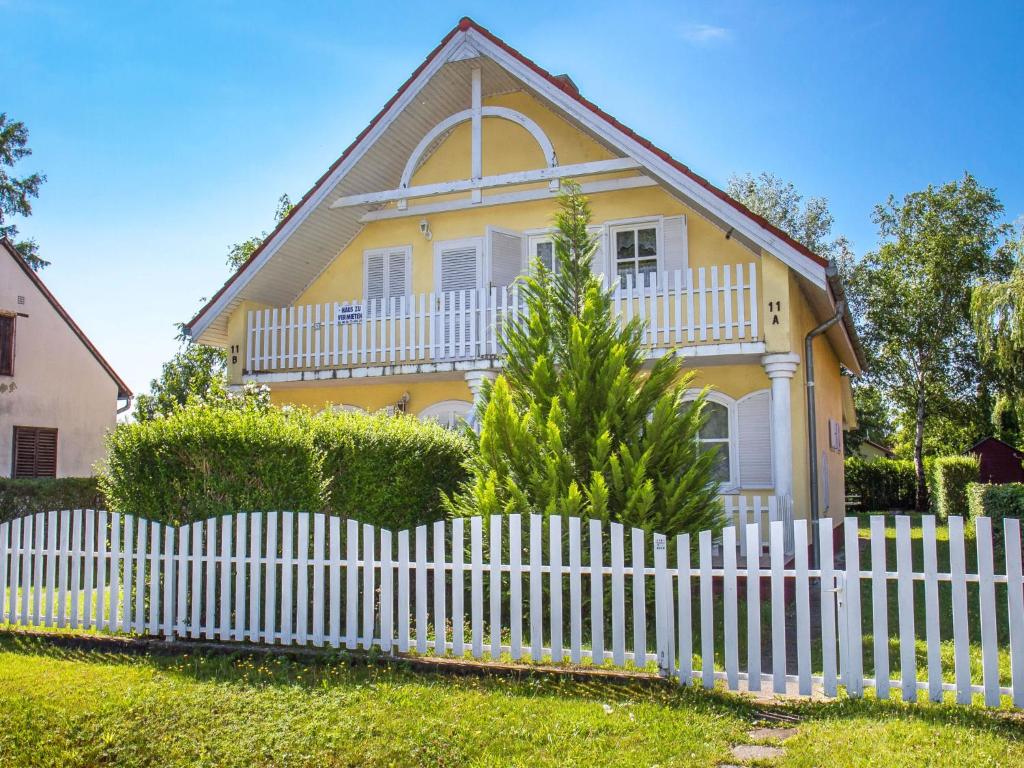Holiday Home Welle by Interhome في بالاتونماريافوردو: سياج خشبي أبيض أمام منزل أصفر