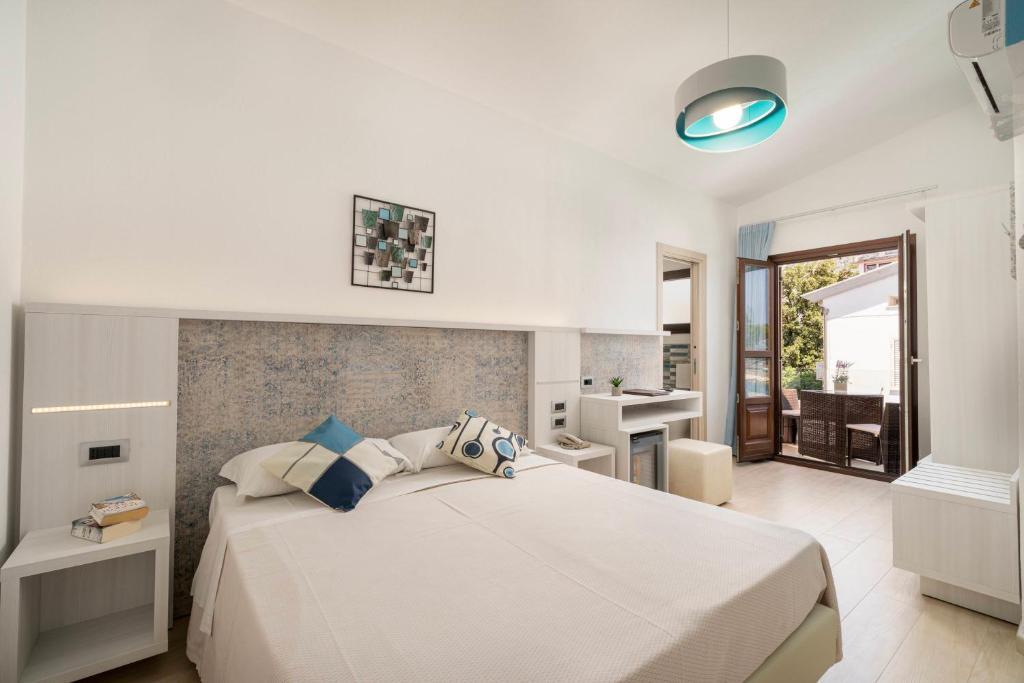 a bedroom with a large white bed and a bathroom at Hotel Ristorante La Conchiglia in Cala Gonone