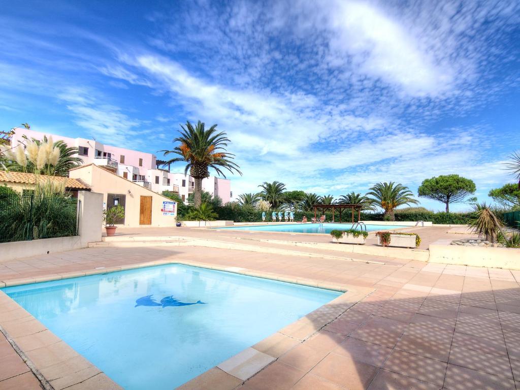 une grande piscine dans une cour avec des palmiers dans l'établissement Apartment Les Capitelles-9 by Interhome, à Saint Cyprien Plage