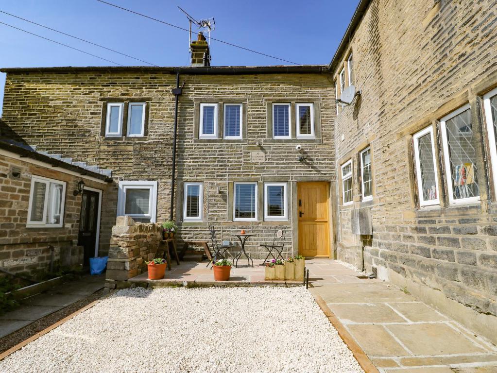 ein Backsteingebäude mit einer Terrasse davor in der Unterkunft Ha'penny Cottage in Holmfirth