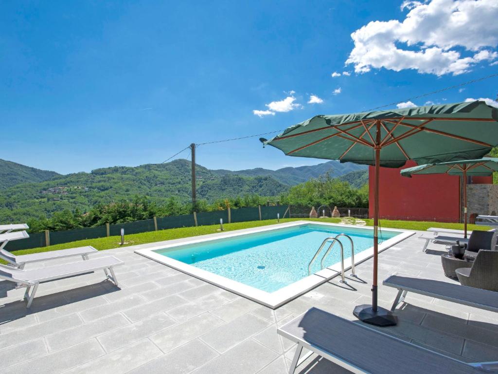 einen Pool mit einem Sonnenschirm, Stühlen und einem Tisch in der Unterkunft Holiday Home Agr- Castello della Mugazzena by Interhome in Tresana