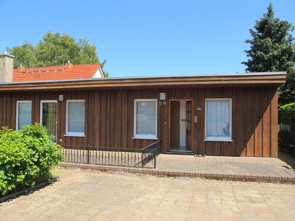 Una pequeña casa de madera con un patio enfrente. en Holiday Home Villa Meike - Insel Poel by Interhome en Kaltenhof