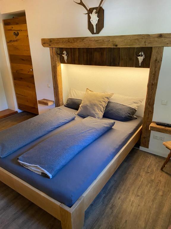 uma cama grande com uma cabeceira em madeira num quarto em Ferienwohnung Königsberger Klosterblick em Ettal