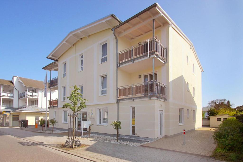 un grand bâtiment blanc avec des balcons sur une rue dans l'établissement zentral aber ruhig, Balkon, gratis Nutzung vom AHOI Erlebnisbad und Sauna in Sellin - Villa Elisenhof FeWo 2, à Göhren