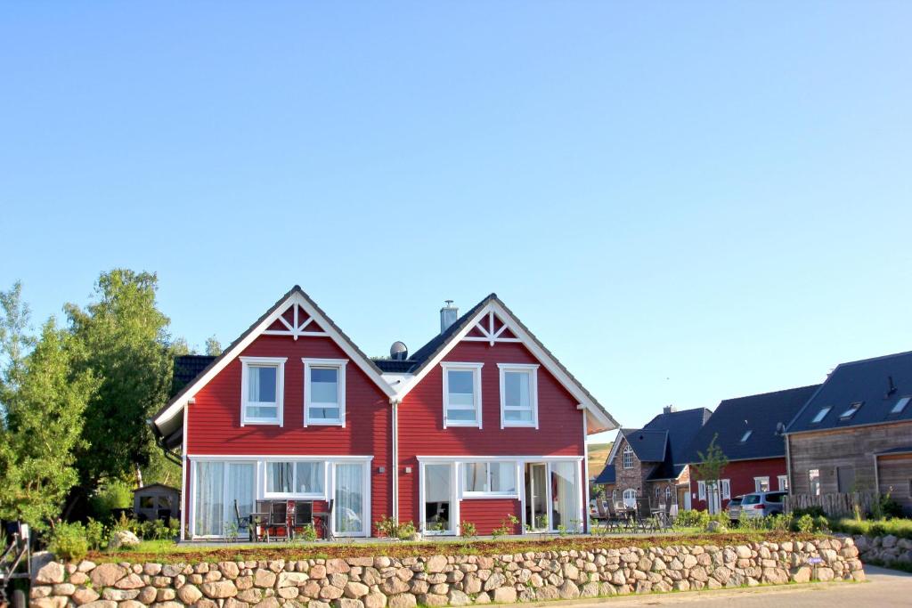 a red house with white windows and a stone wall at Ferienhaus TimpeTe Haus Backbord - Terrasse, Meerblick, Sauna in Gager