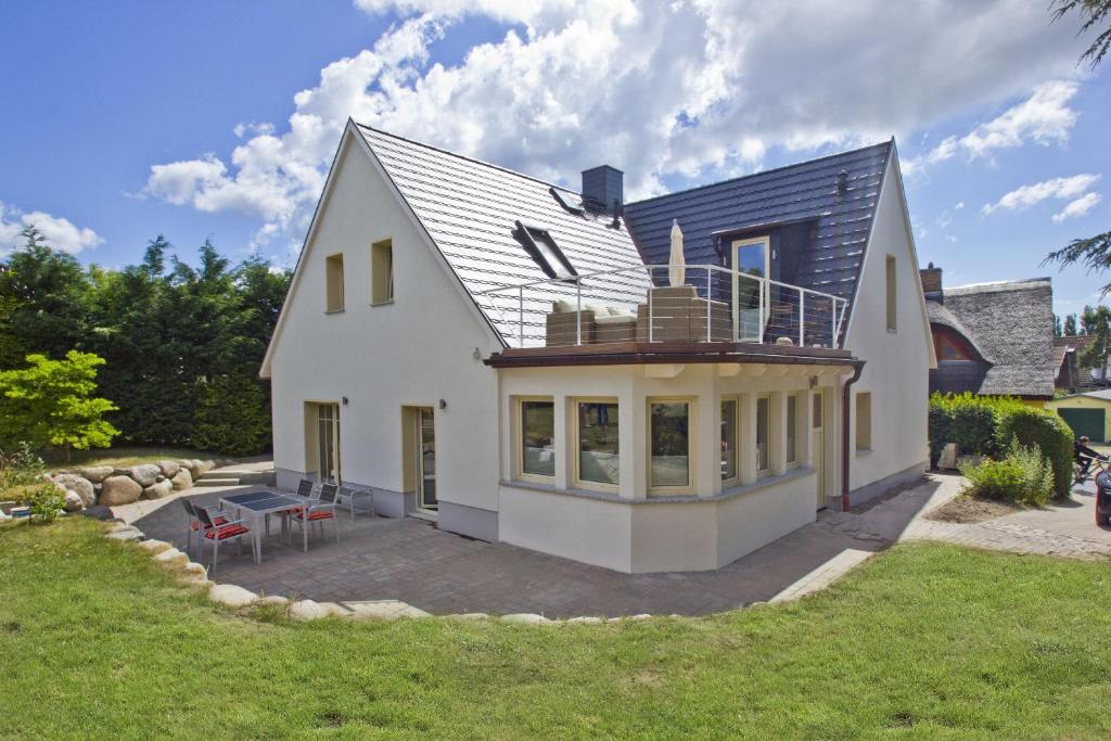 Una gran casa blanca con una terraza encima. en Ferienhaus Auszeit FeWo 03 - Dachterrasse, ruhige Lage, en Middelhagen
