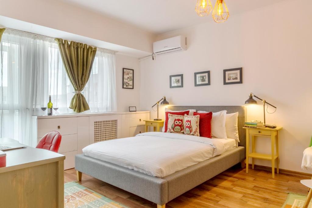 1 dormitorio con cama, escritorio y ventana en Piata Victoriei by MRG Apartments, en Bucarest