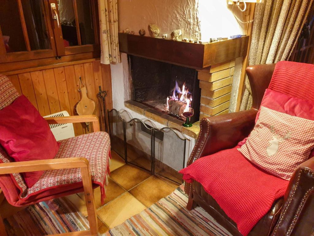 a living room with two chairs and a fireplace at Chalet Henri by Interhome in Moleson