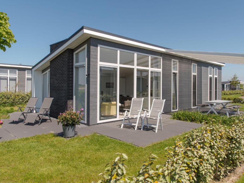 a modular home with chairs and a patio at Holiday Home Water Resort Oosterschelde - nr- 47A by Interhome in Wemeldinge