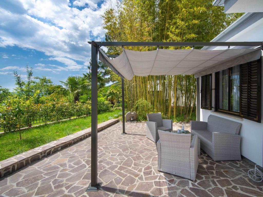 eine Terrasse mit einem Baldachin, Stühlen und einem Tisch in der Unterkunft Holiday Home Erminia by Interhome in Lovran