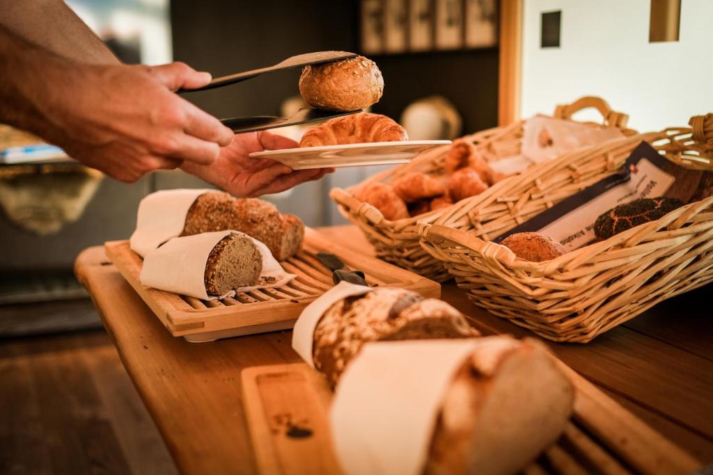 eine Person serviert Essen auf einem Tisch mit Brot in der Unterkunft Mountain Paradise in Zermatt