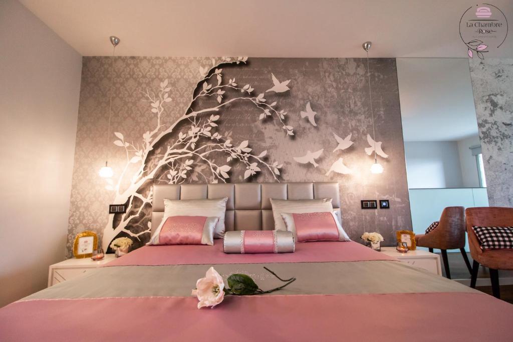 a bedroom with a large bed with a tree mural at La Chambre Rose in Ponta do Sol