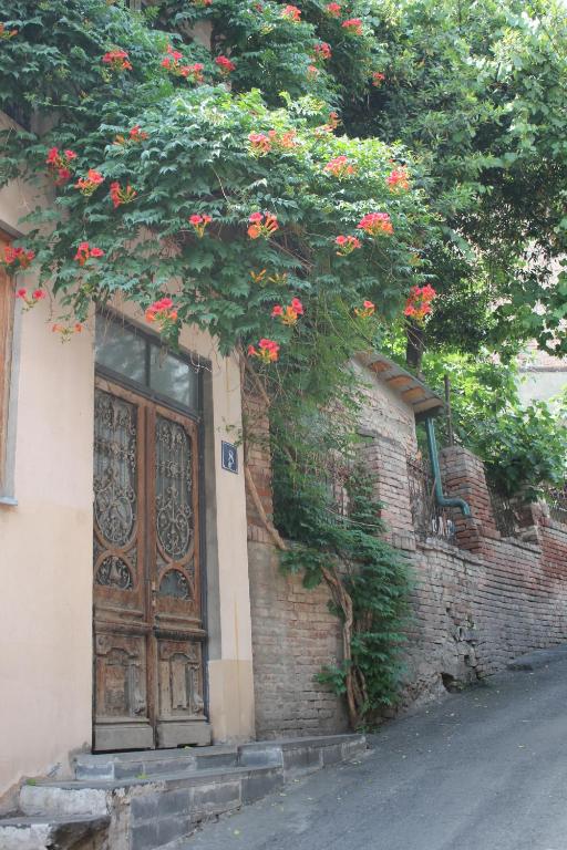 a building with a door and a tree with red flowers at Valiko in Tbilisi City