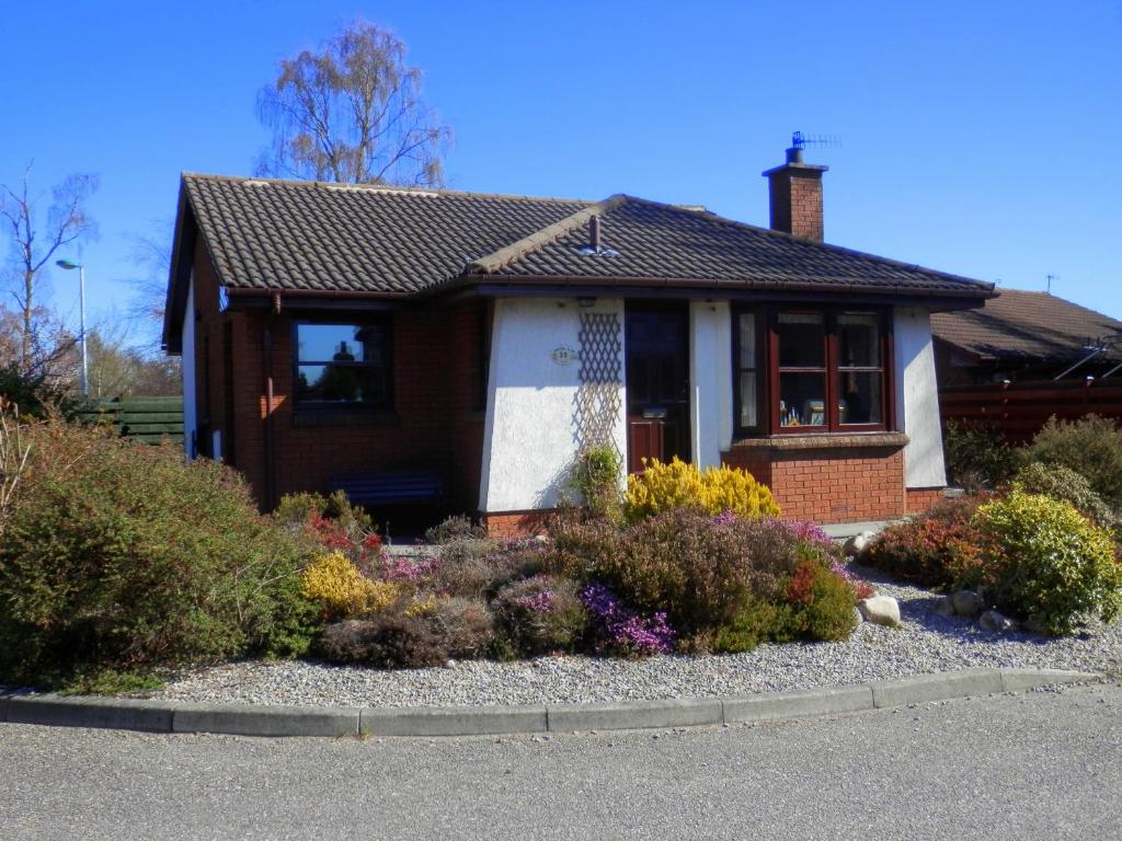 a small house with flowers in the front yard at Cairngorm Highland Bungalows in Aviemore