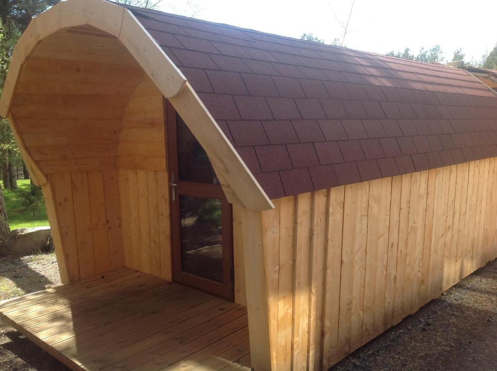 a large wooden dog house with a pitched roof at Camping Pod Heaven in Brackla