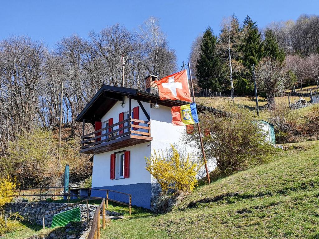 una pequeña casa en una colina con una bandera en Holiday Home Cà Listra by Interhome en Gudo