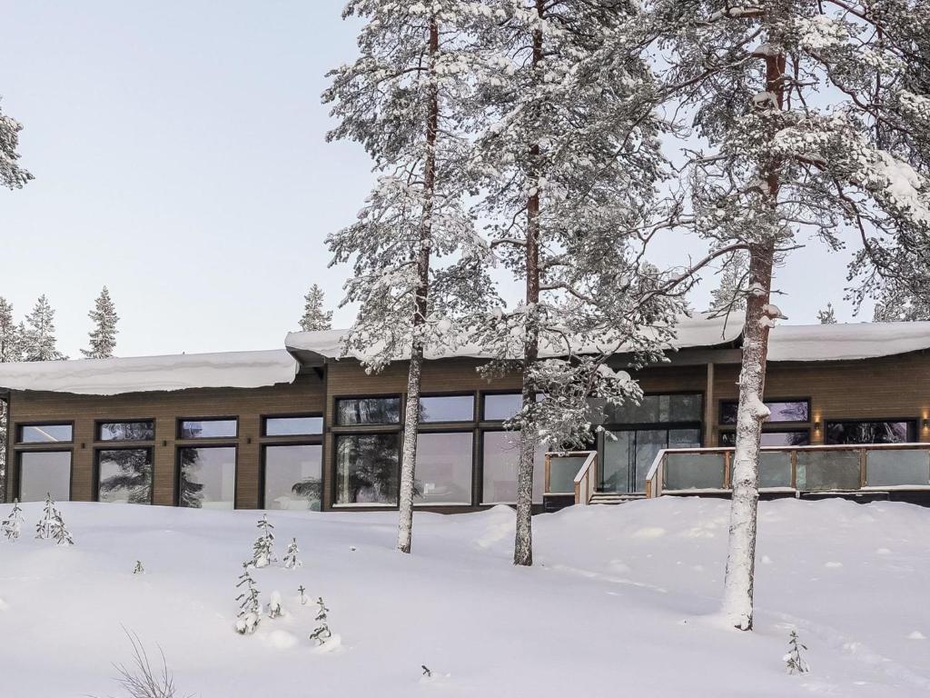 a building covered in snow with trees in the foreground at Holiday Home Villa kallas by Interhome in Karjalaisenniemi