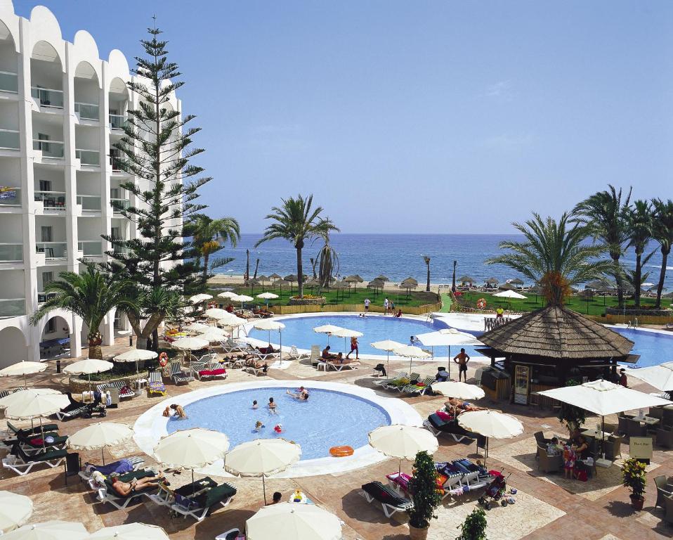 an overhead view of a swimming pool with umbrellas and the ocean at Ona Marinas de Nerja Spa Resort in Nerja