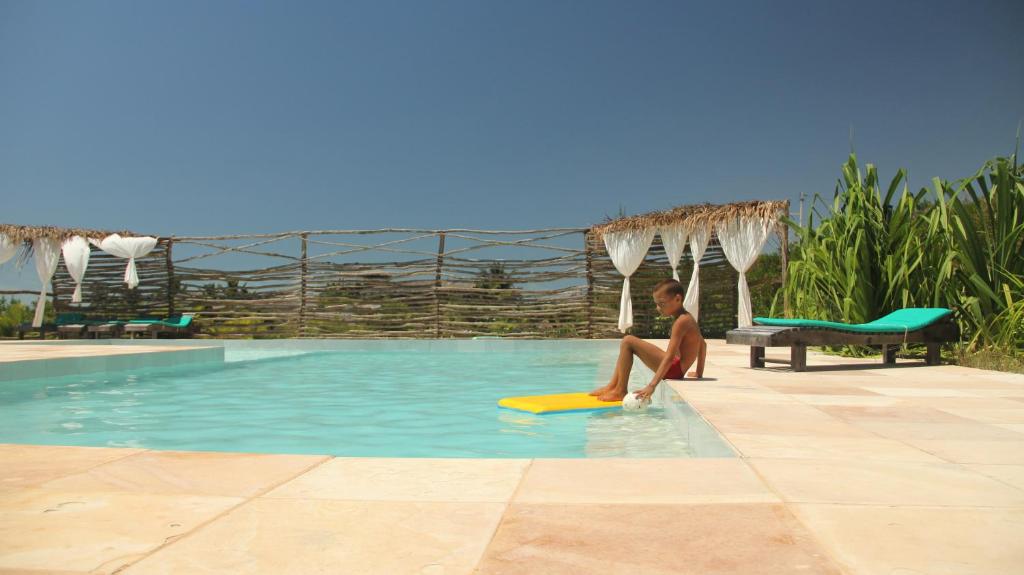 a man sitting on a surfboard in a swimming pool at Eco Kite Dunas in Prea