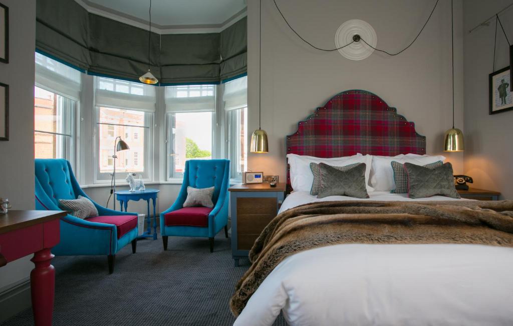 a bedroom with a bed and two blue chairs at Dog and Fox in London