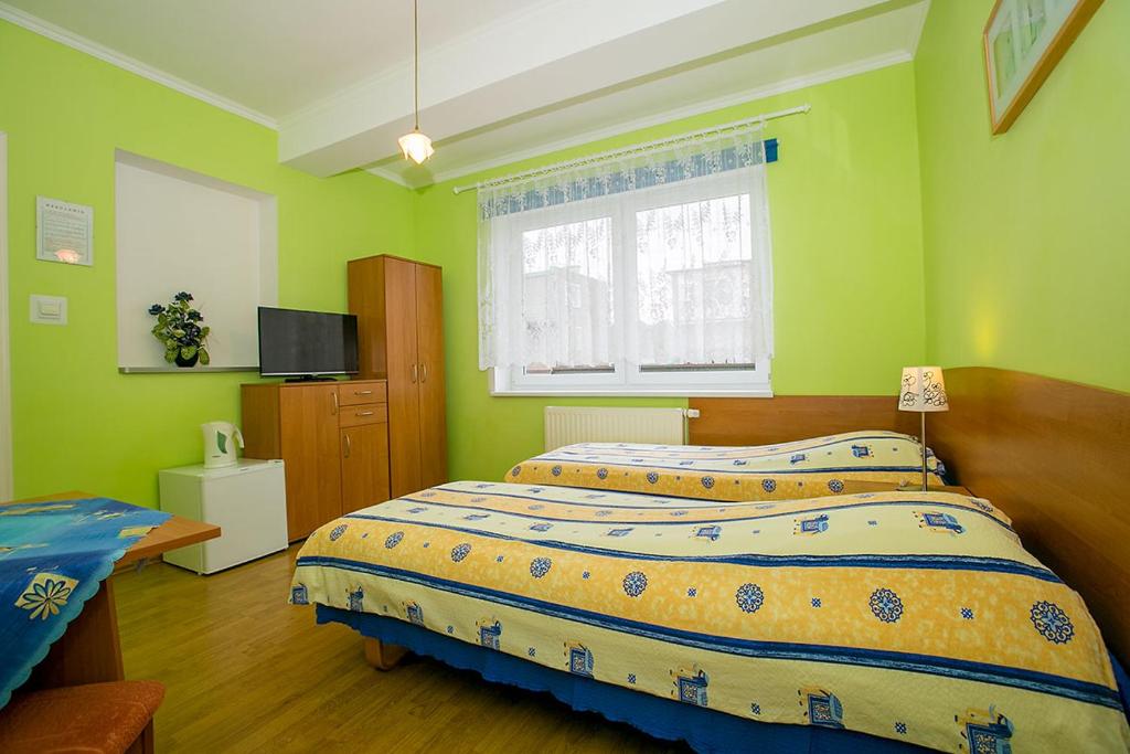 a green bedroom with two beds and a window at Willa Anna in Międzyzdroje
