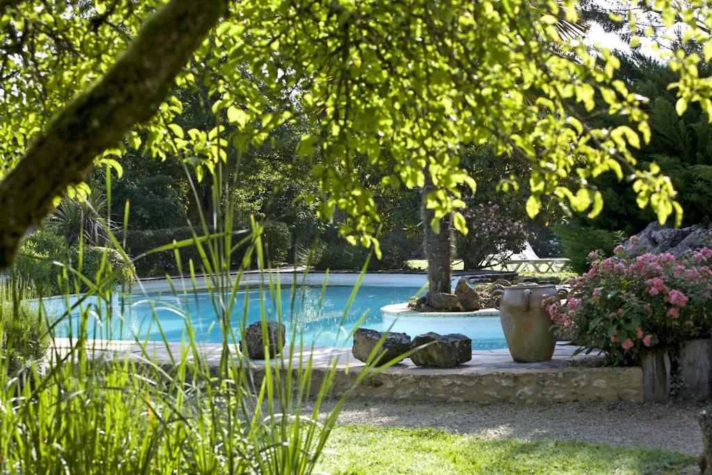 a swimming pool in a garden with some vases at La Roseraie Hôtel Restaurant in Montignac