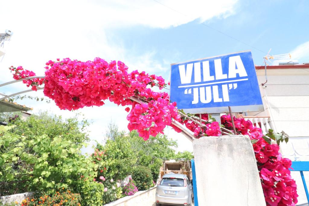 a sign for a villa in jupiter with pink flowers at Villa Juli Ksamil in Ksamil