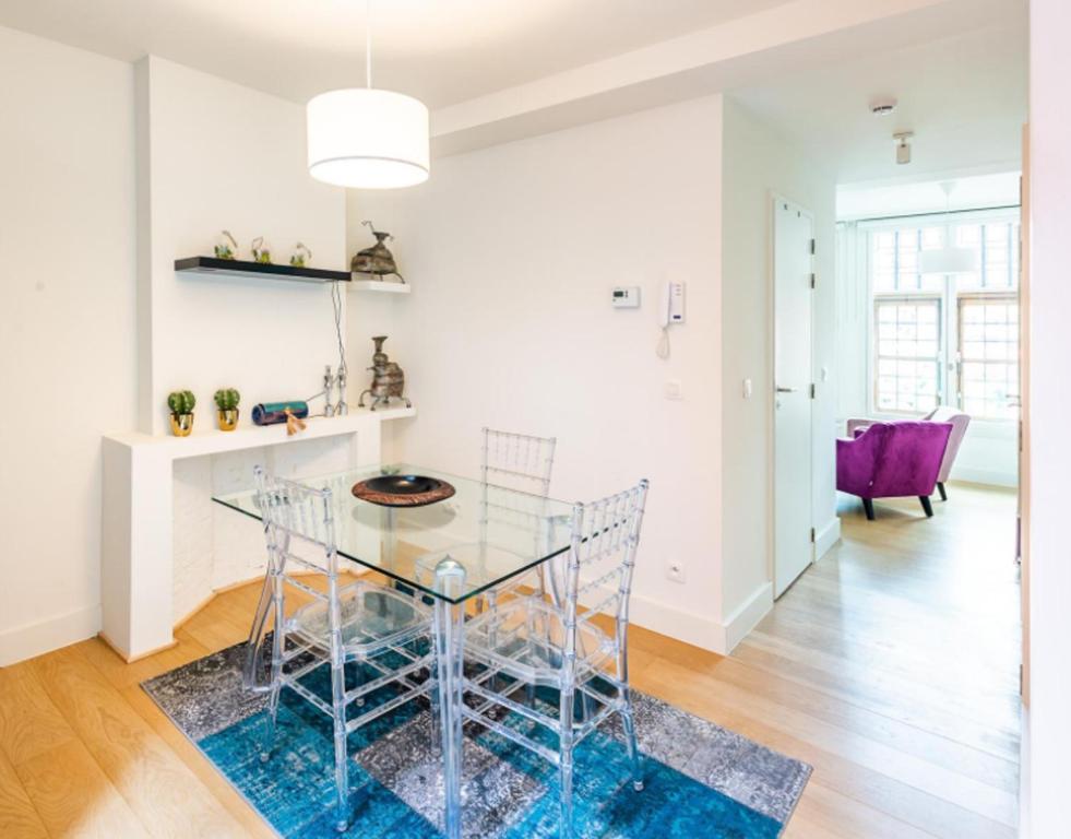 une salle à manger avec une table en verre et des chaises violettes dans l'établissement Antwerp old town appartment, à Anvers