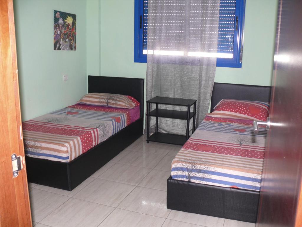 um quarto com 2 camas, uma mesa e uma janela em APARTAMENTOS PALACIO RIAD LARACHE em Larache