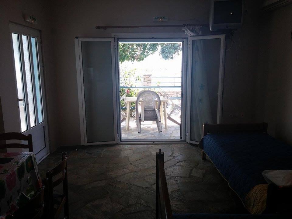 um quarto com uma porta que abre para um pátio com uma cadeira em Holiday Tolofona Beach em Erateini