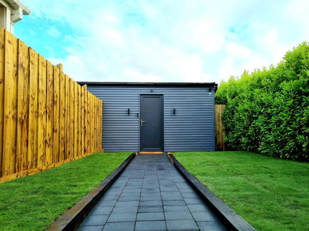 a garage with a fence and a grass yard at Yaseva Lodge, Stylish Country Retreat for 2, Hot Tub, Exceptional Views! in Carr