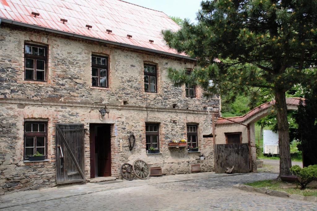 an old stone building with a red roof at Na koňské farmě in Malečov